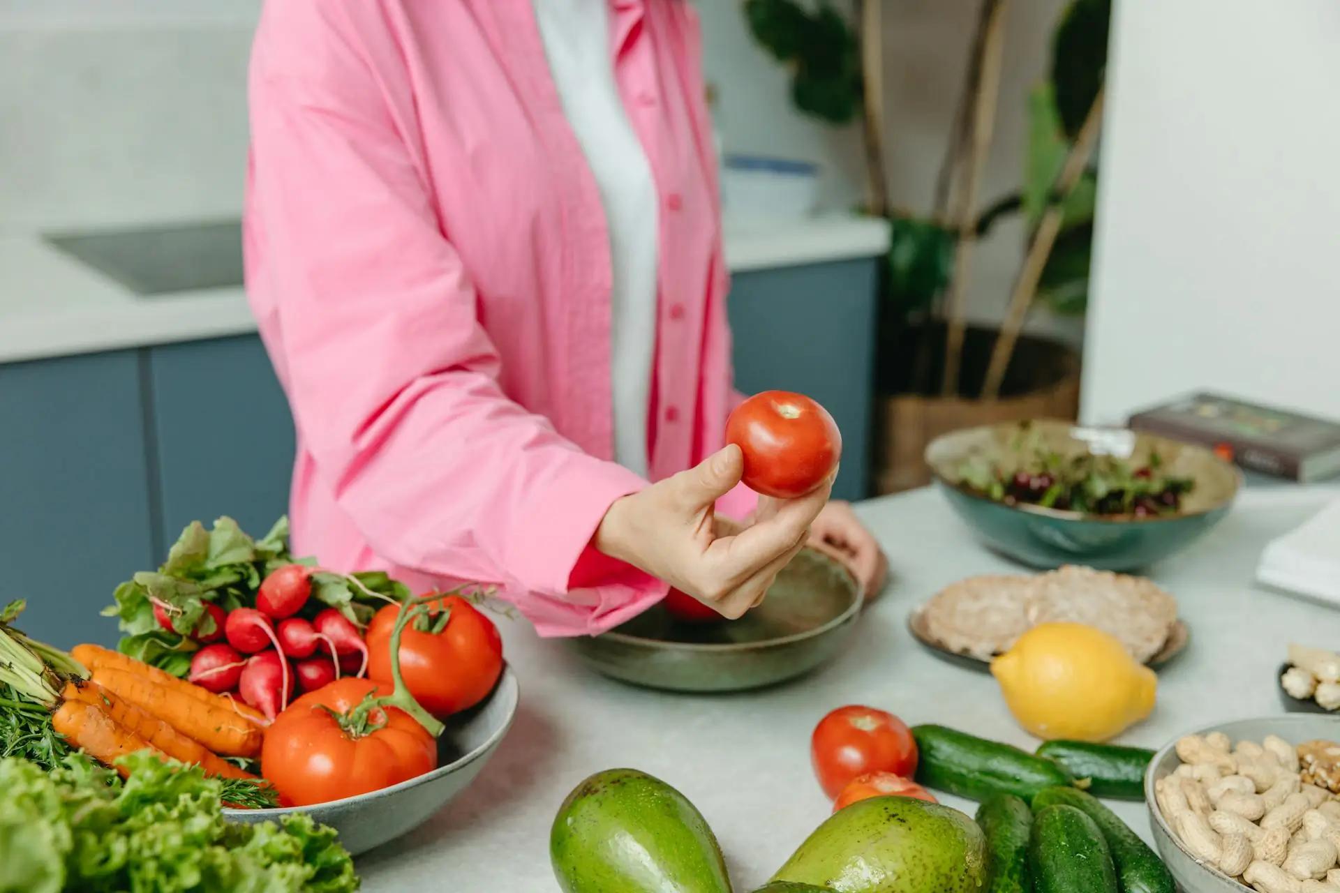 Groupe de personnes avec des ordinateurs portables à une table avec des produits frais, dans une cuisine moderne.